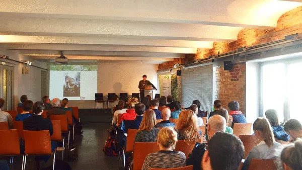 Konferenzteilnehmerinnen und Konferenzteilnehmer von hinten mit Blick auf Redner